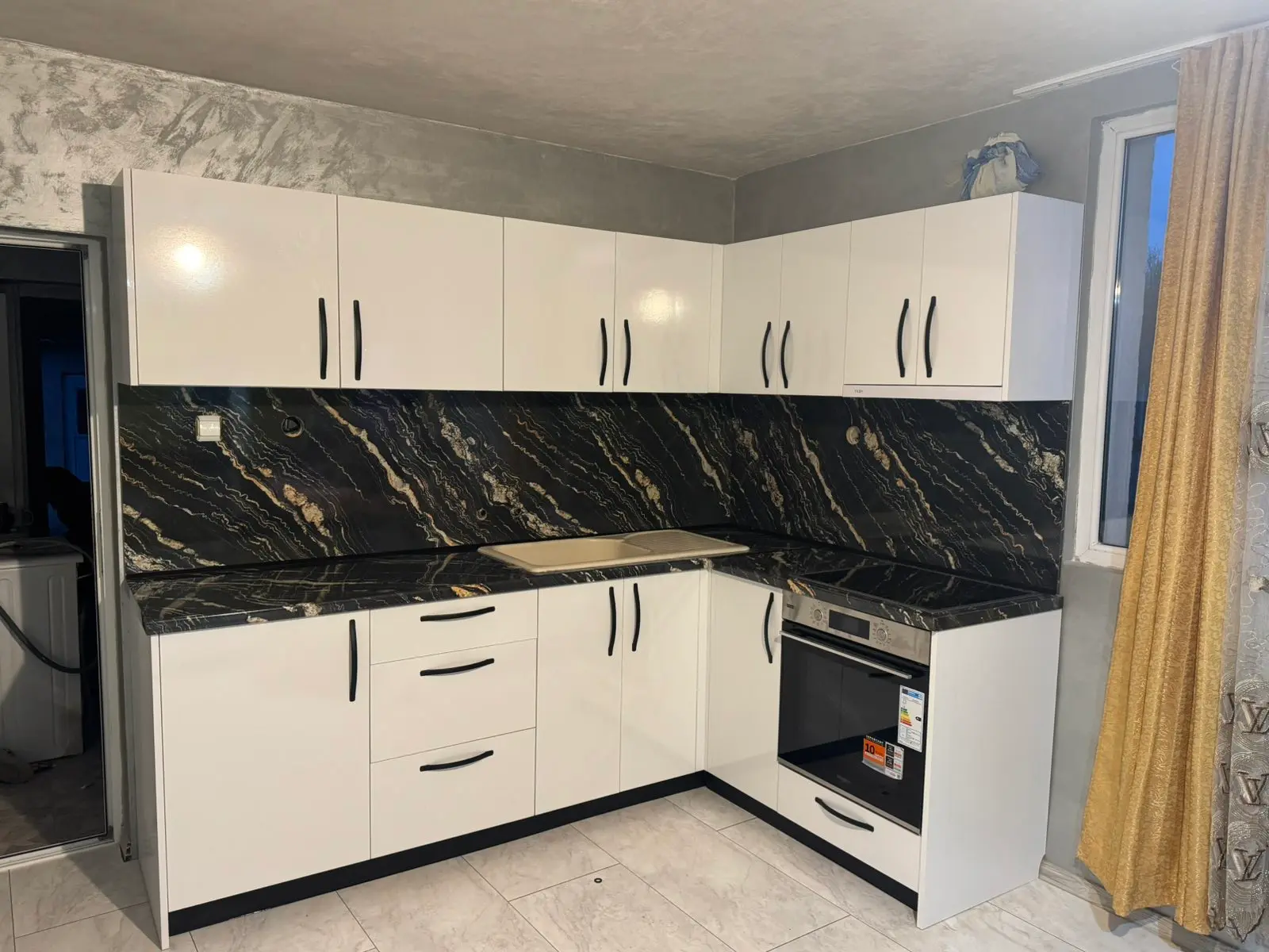 Г-образна бяла кухня по поръчка с плот от технически камък черен мрамор — проект Бургас