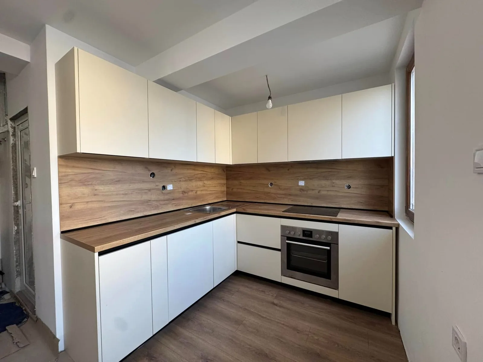 Г-образна бяла кухня по поръчка с дървен плот и вградена фурна — проект Бургас