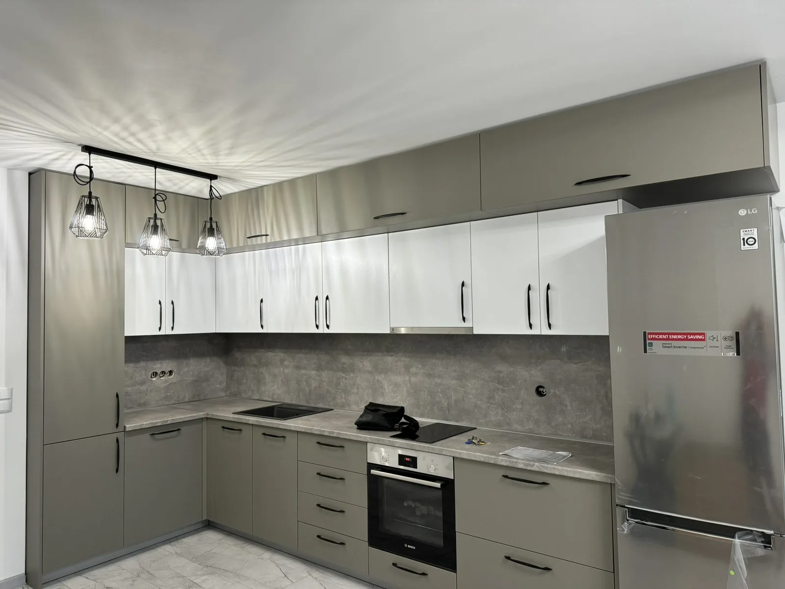 Г-образна кухня по поръчка в сиво и бяло с бетонов гръб и осветление — проект Бургас